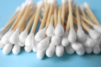 Photo of Heap of clean cotton buds on light blue background, closeup