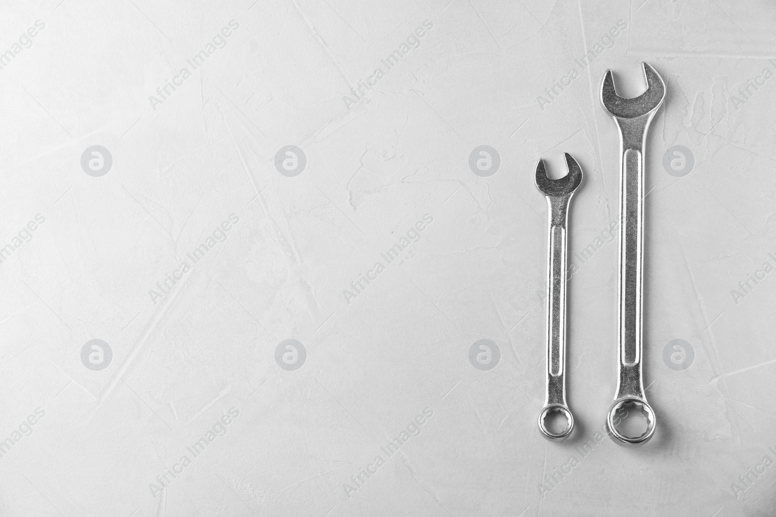 Photo of New wrenches on grey background, top view with space for text. Plumber tools