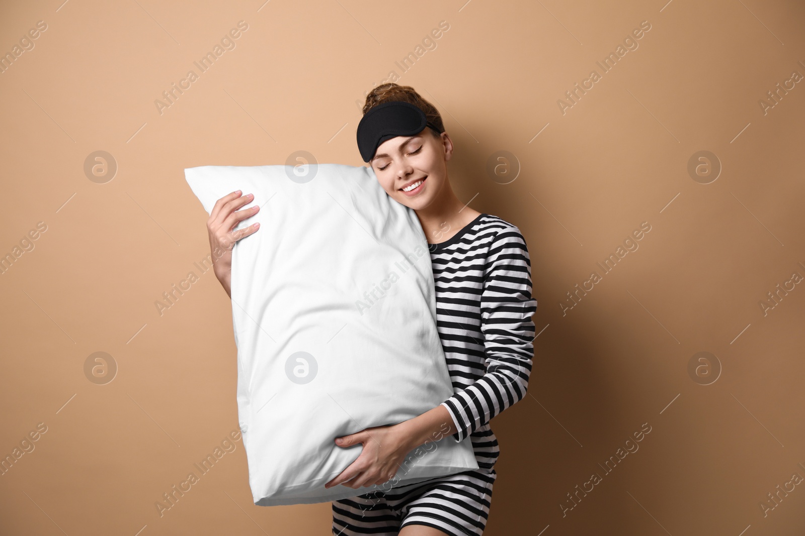 Photo of Beautiful woman with pillow on beige background. Bedtime