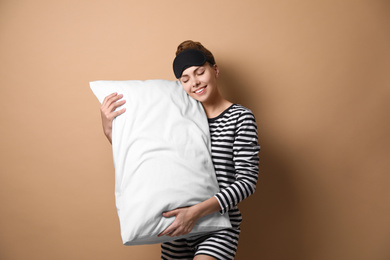 Photo of Beautiful woman with pillow on beige background. Bedtime