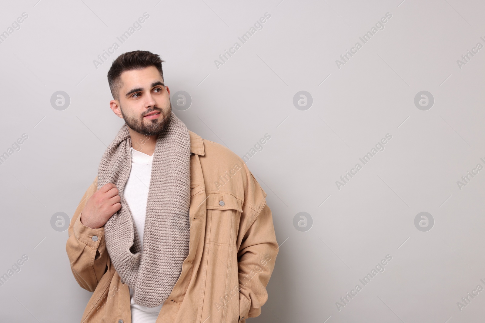 Photo of Handsome man in warm scarf on light grey background. Space for text