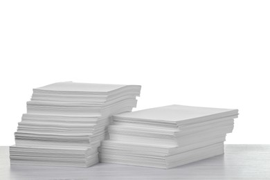 Photo of Stacks of paper sheets on light wooden table against white background