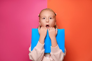 Emotional little girl with book on colorful background