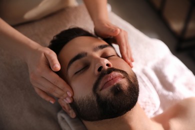 Young man receiving facial massage in beauty salon