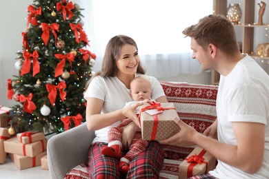 Photo of Happy couple with baby celebrating Christmas together at home