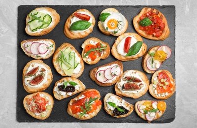 Different bruschettas on light grey marble table, top view