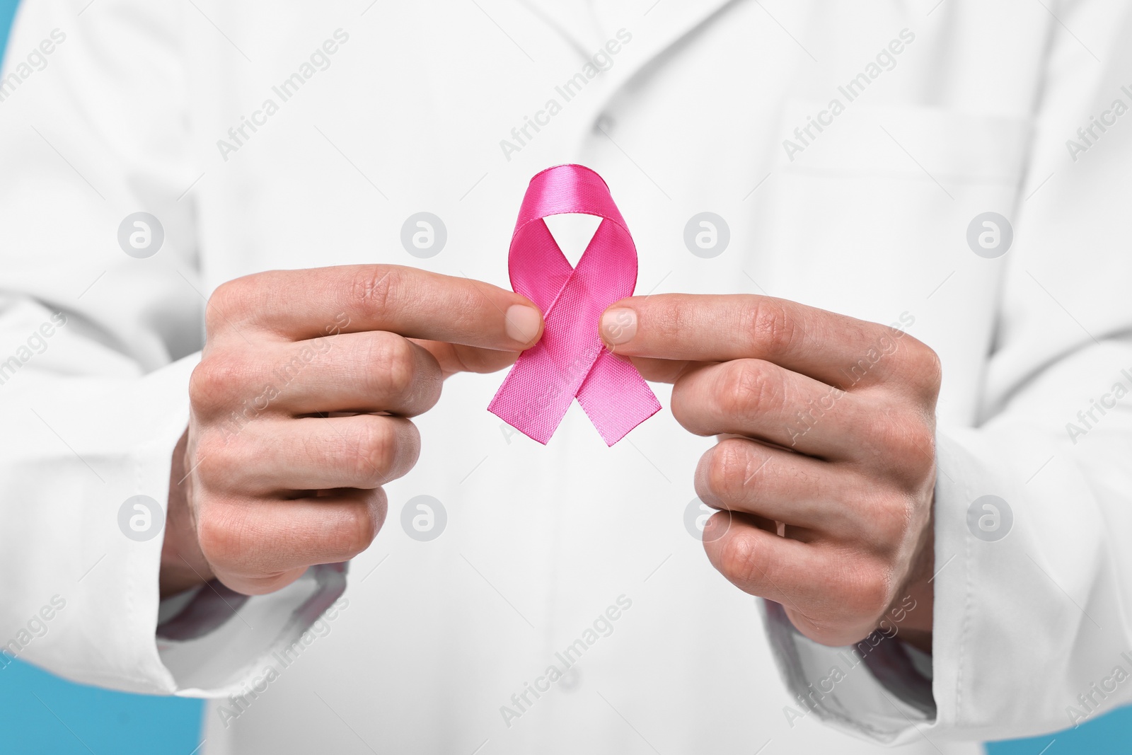 Photo of Mammologist giving pink ribbon, closeup. Breast cancer awareness