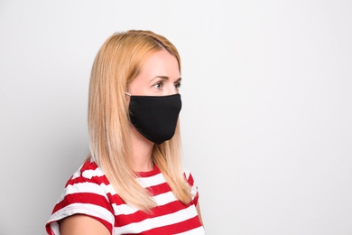 Photo of Woman wearing handmade cloth mask on white background, space for text. Personal protective equipment during COVID-19 pandemic