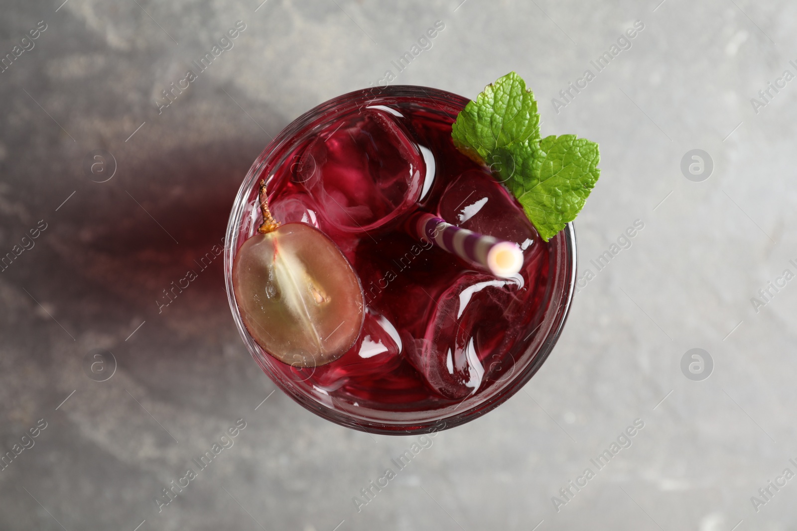 Photo of Delicious grape soda water on grey table, top view. Refreshing drink