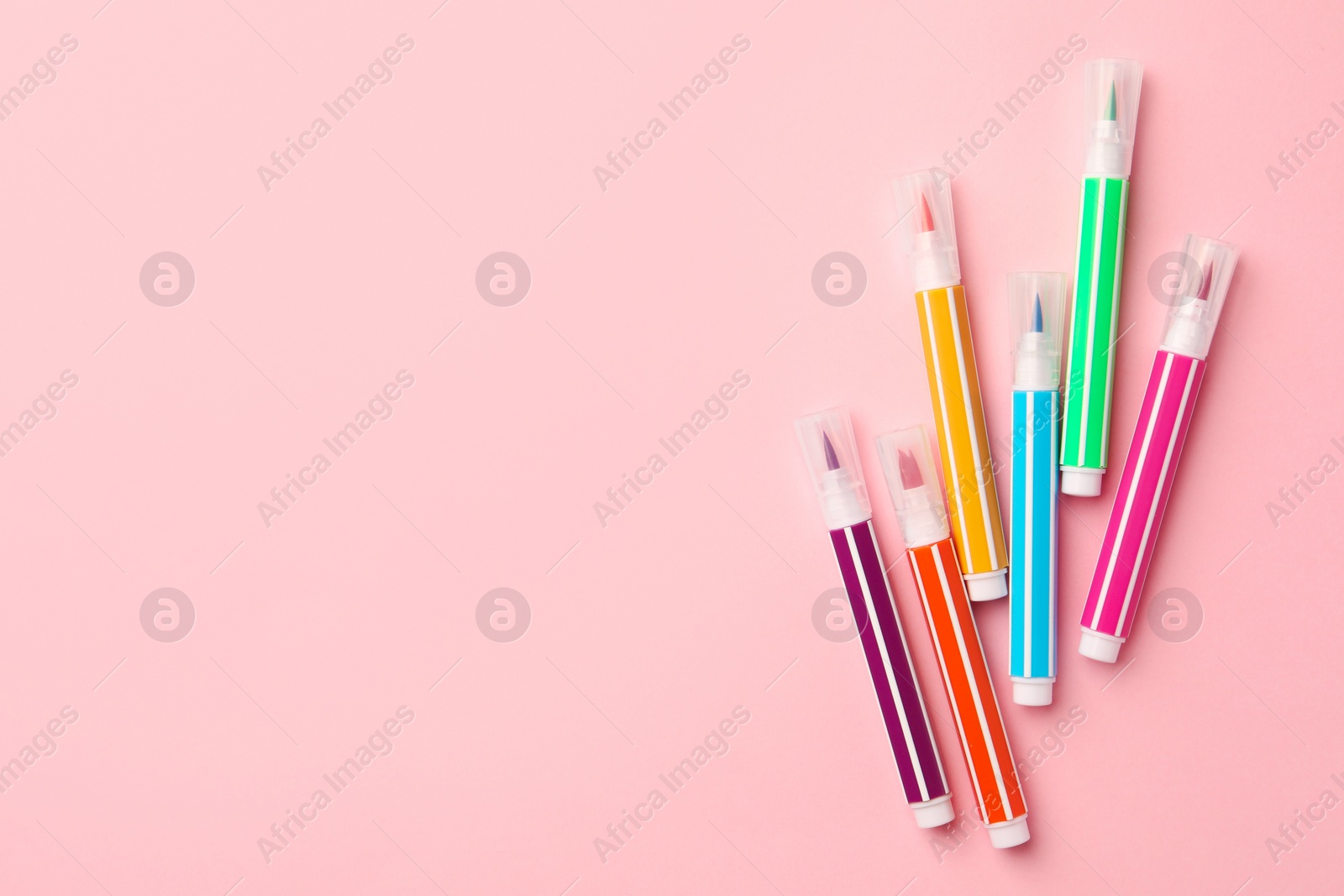 Photo of Many bright markers on pink background, flat lay. Space for text