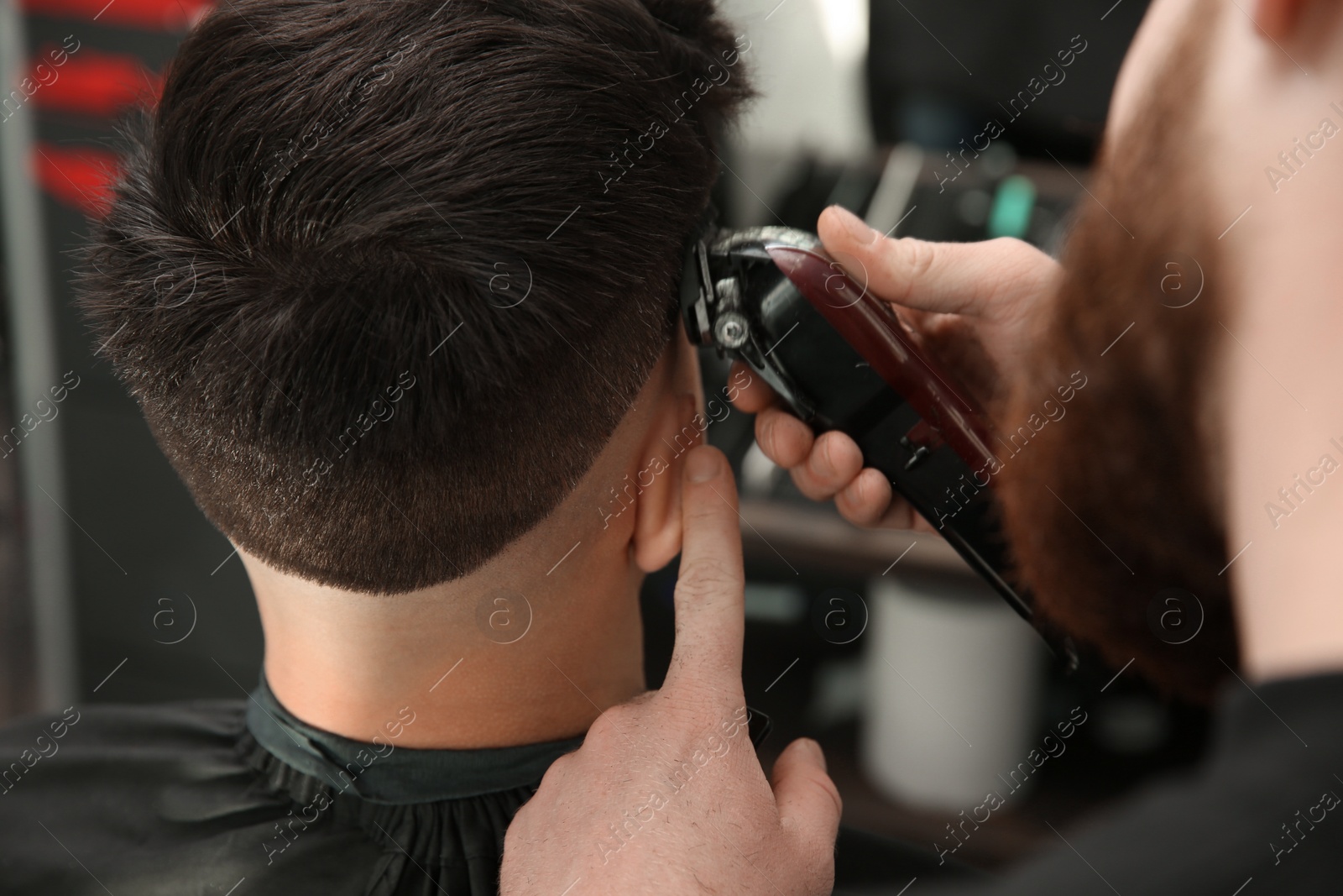 Photo of Professional barber making stylish haircut in salon, closeup