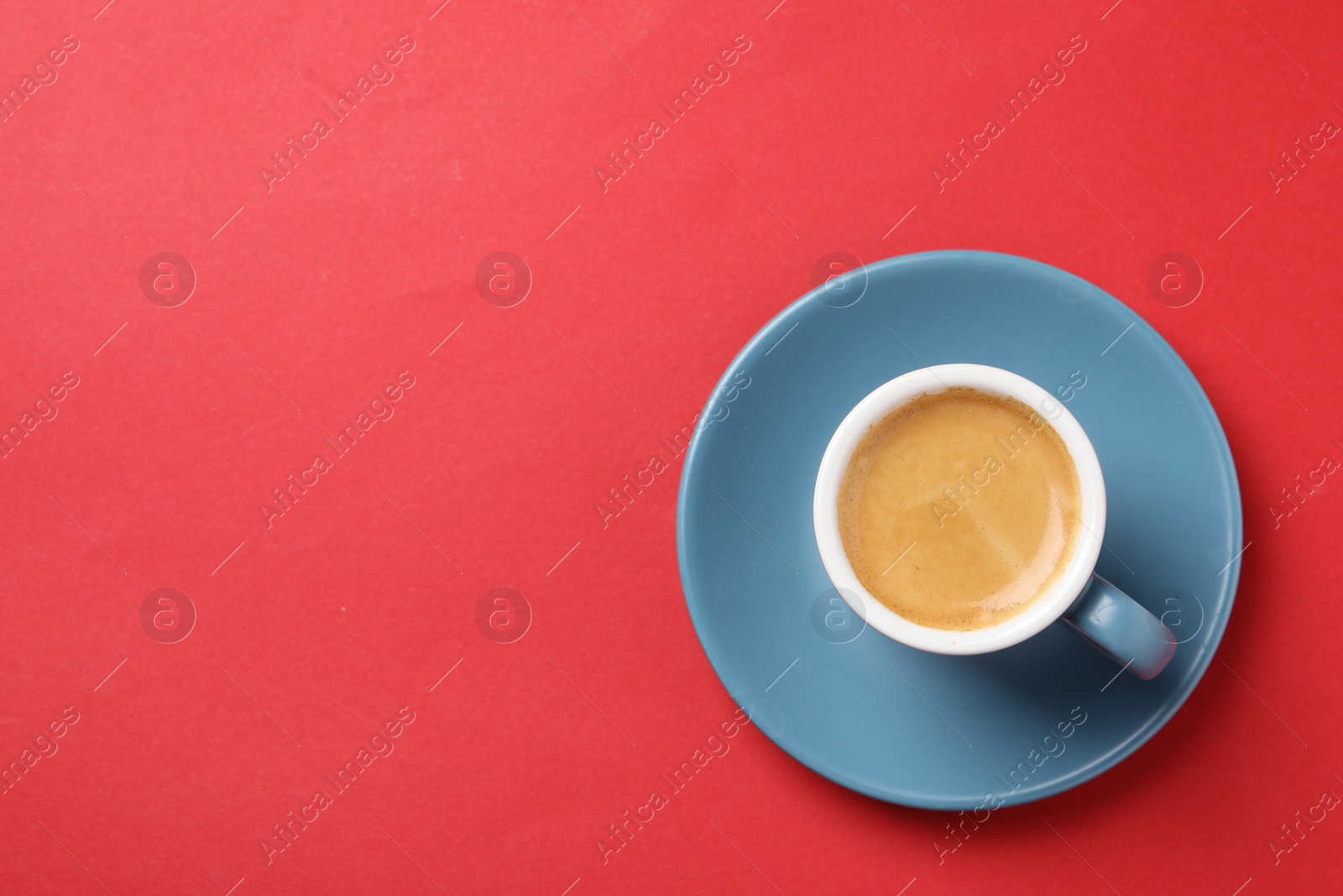 Photo of Aromatic coffee in cup on red background, top view. Space for text