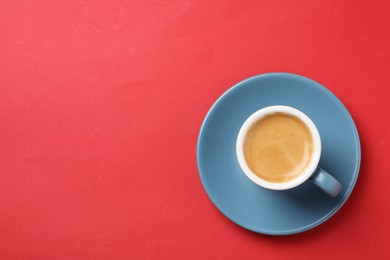 Photo of Aromatic coffee in cup on red background, top view. Space for text