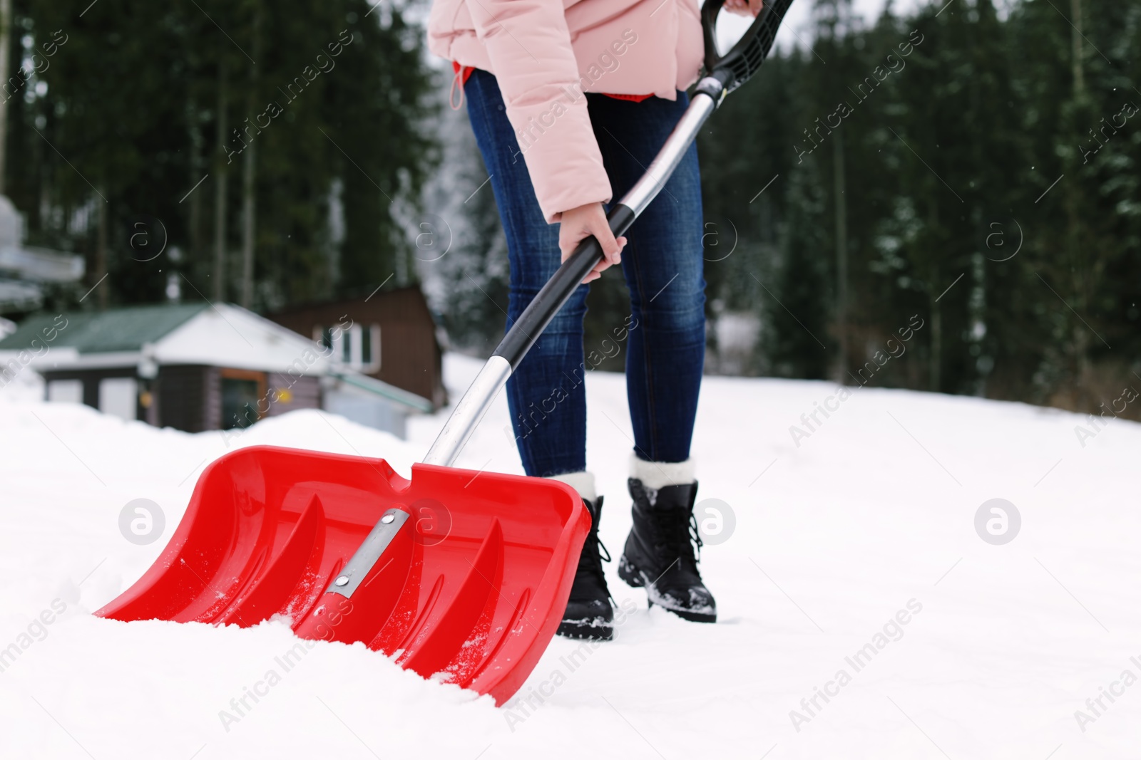 Photo of Woman removing snow with shovel near house