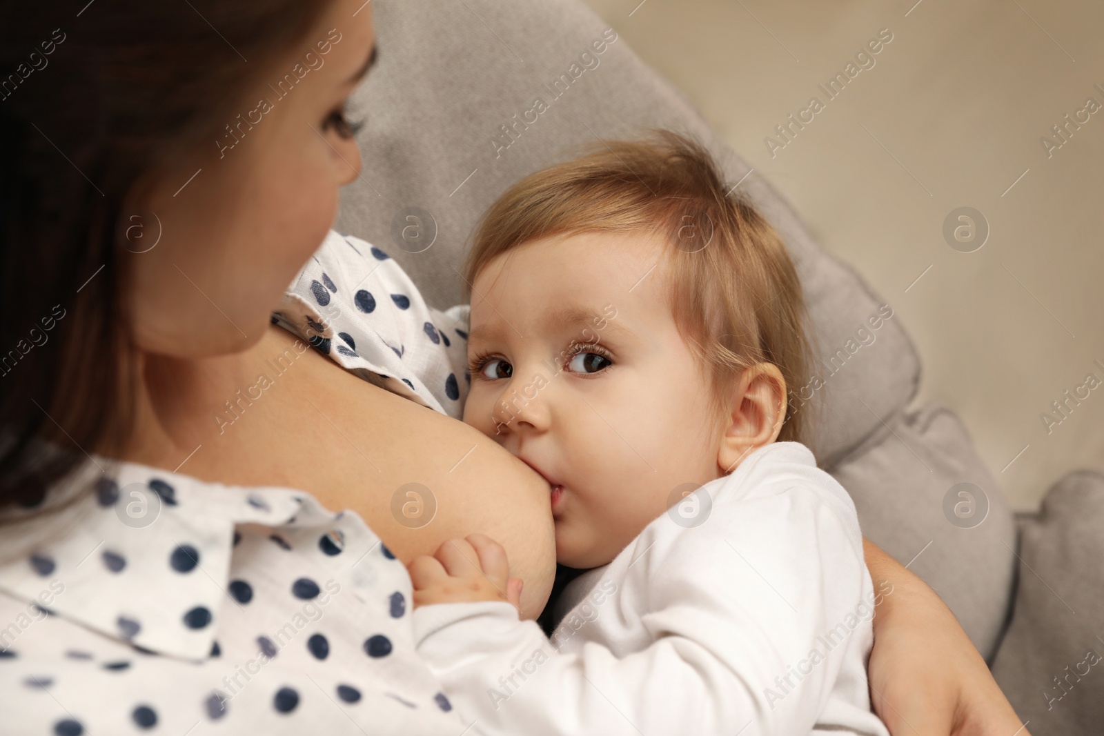 Photo of Woman breastfeeding her little baby at home, closeup