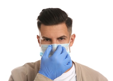 Man in medical gloves putting on protective face mask against white background