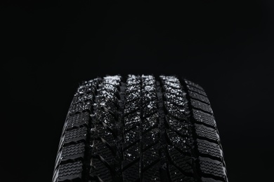 Photo of Snowy winter tire on black background, closeup