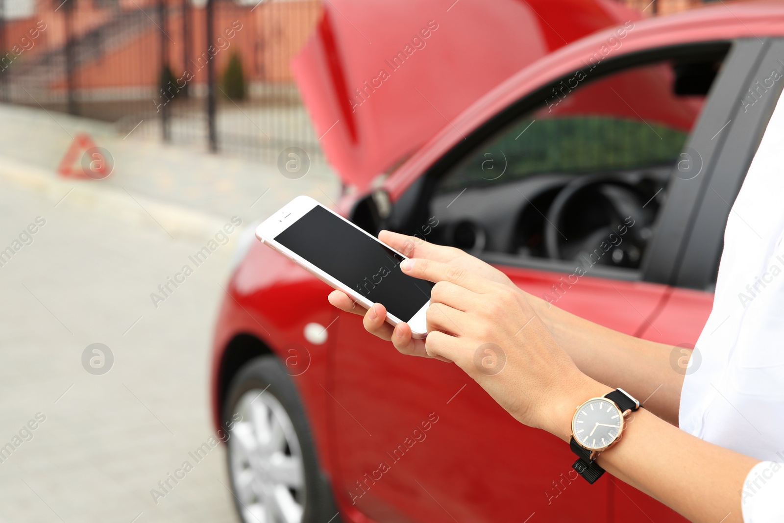 Photo of Woman with smartphone near broken car, closeup