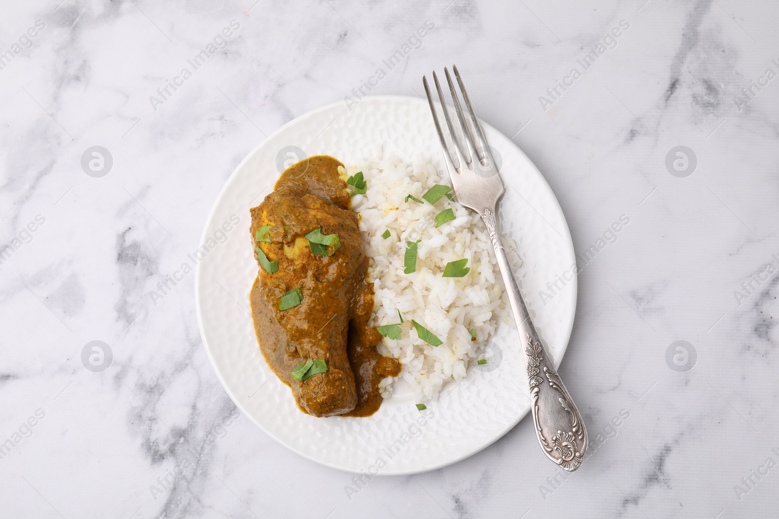 Photo of Delicious rice and chicken with curry sauce on white marble table, top view