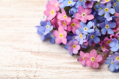 Photo of Beautiful blue and pink Forget-me-not flowers on white wooden table, closeup. Space for text