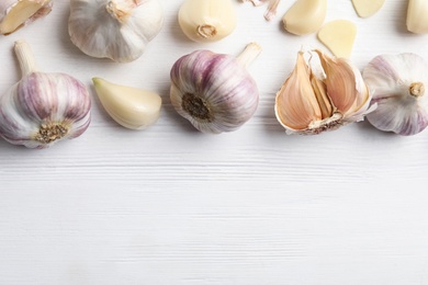 Photo of Fresh organic garlic on white wooden table, flat lay. Space for text