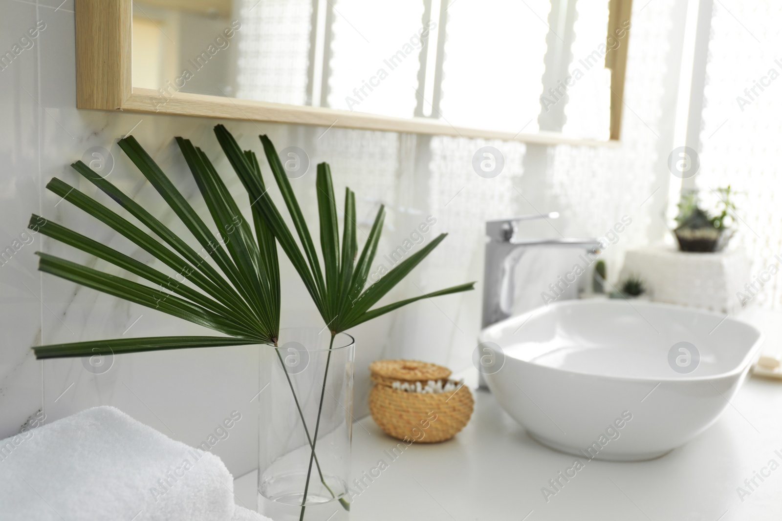 Photo of Tropical palm leaves in stylish bathroom interior