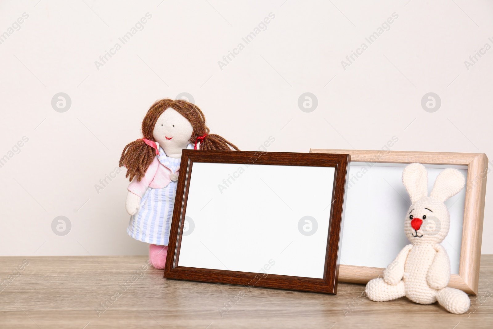 Photo of Photo frames and adorable toys on table against light background, space for text. Child room elements