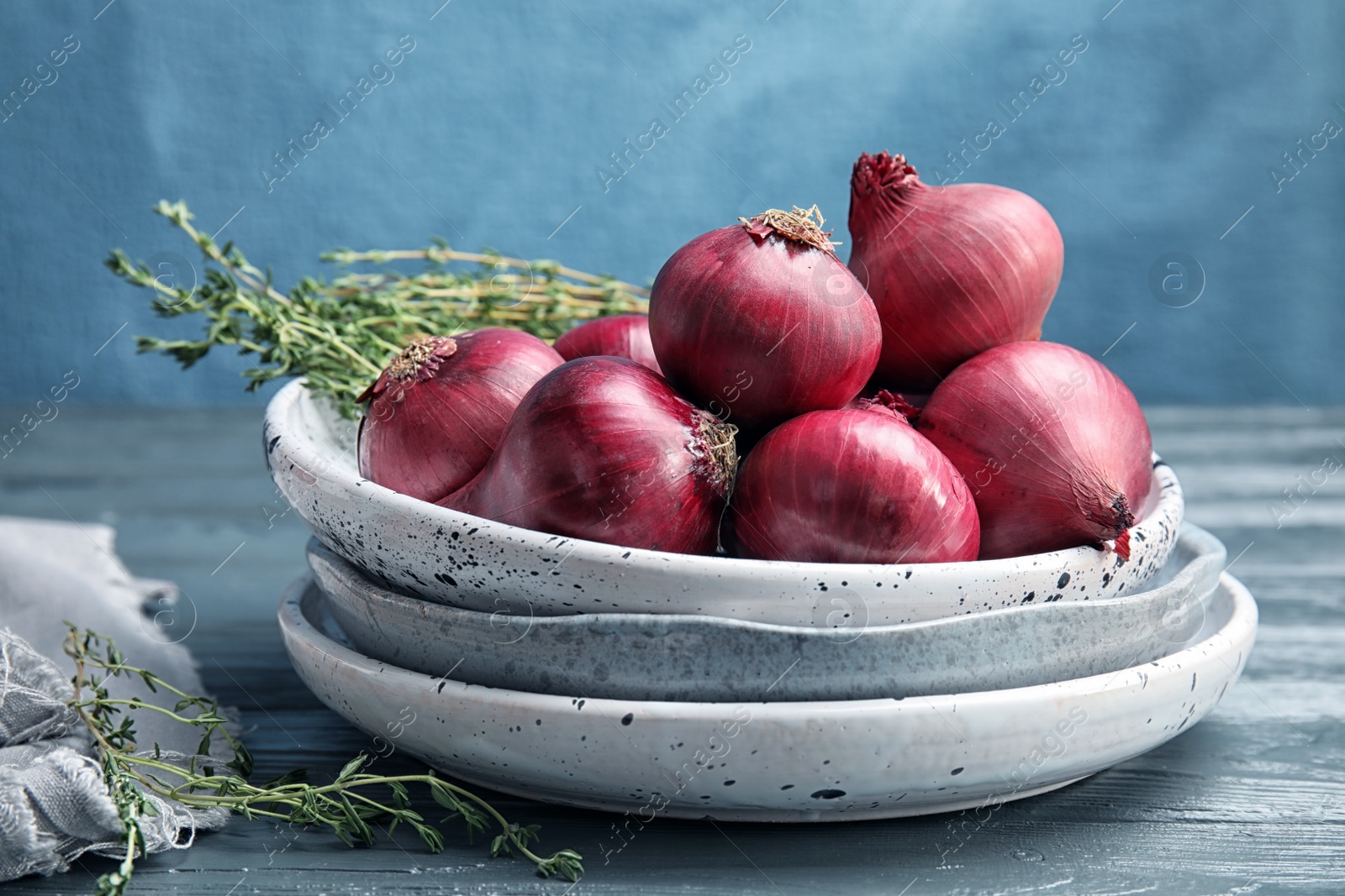 Photo of Plates with ripe red onions on wooden table