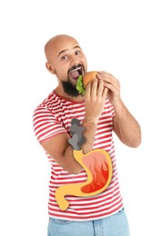 Image of Improper nutrition can lead to heartburn or other gastrointestinal problems. Man eating burger on white background. Illustration of stomach with fire and smoke as acid indigestion