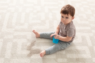 Baby sitting on carpet with empty glass