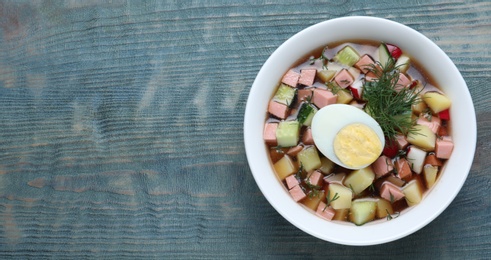 Photo of Delicious cold okroshka with kvass and space for text on blue wooden table, top view. Traditional Russian summer soup