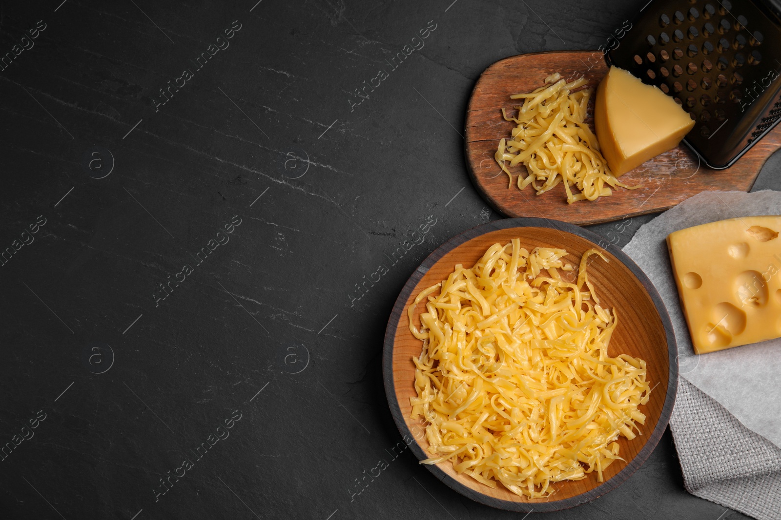 Photo of Flat lay composition with grated cheese on black table. Space for text