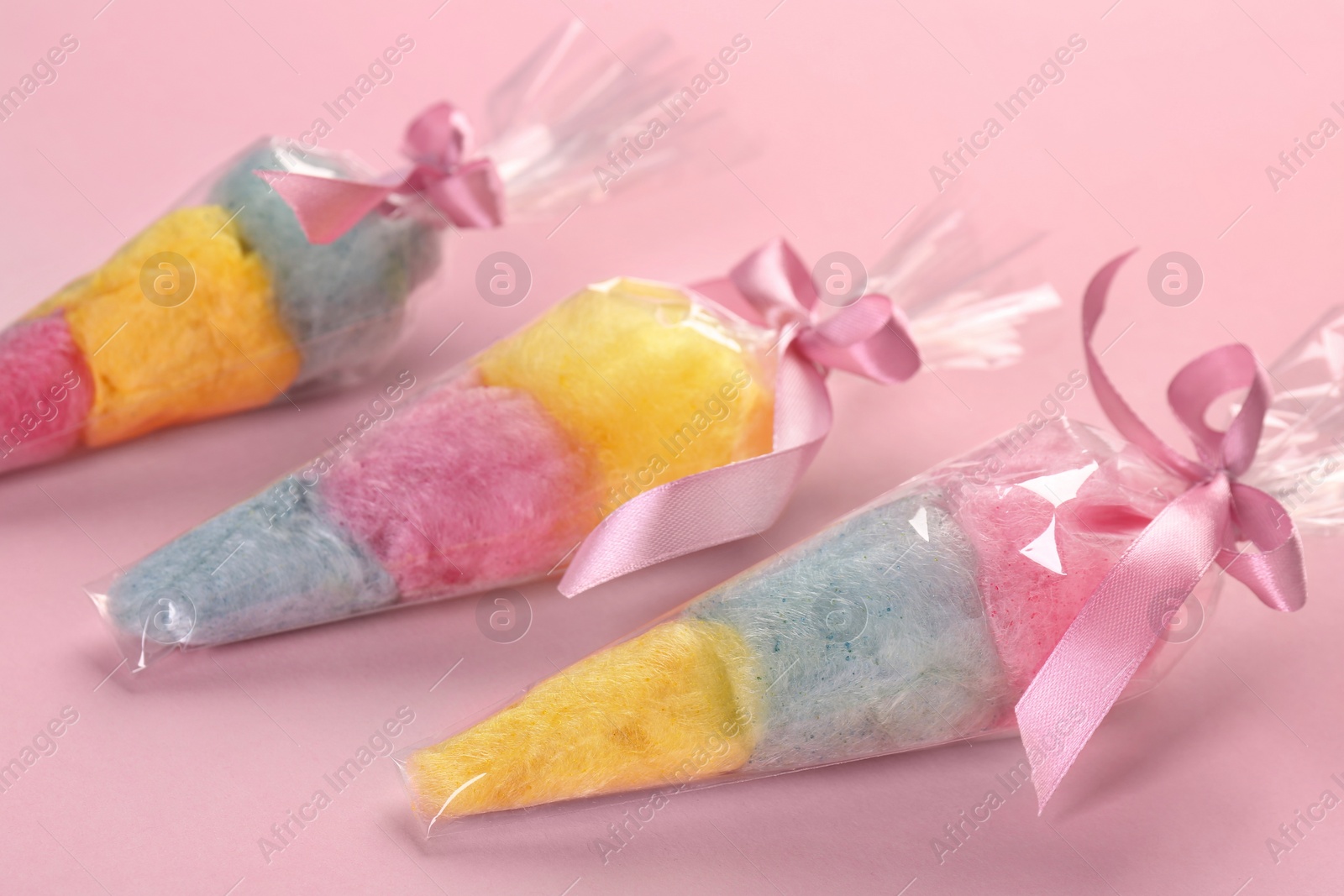 Photo of Packaged sweet cotton candies on pink background