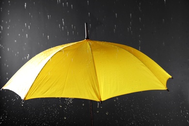 Photo of Bright umbrella under rain on dark background