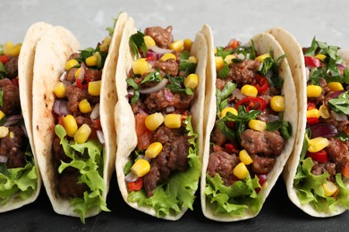 Photo of Delicious tacos with meat and vegetables on table, closeup