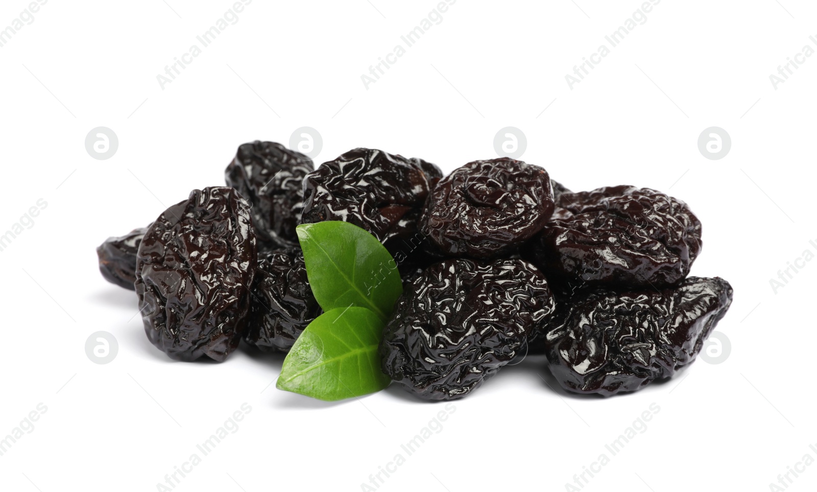 Photo of Heap of sweet dried prunes and green leaves on white background