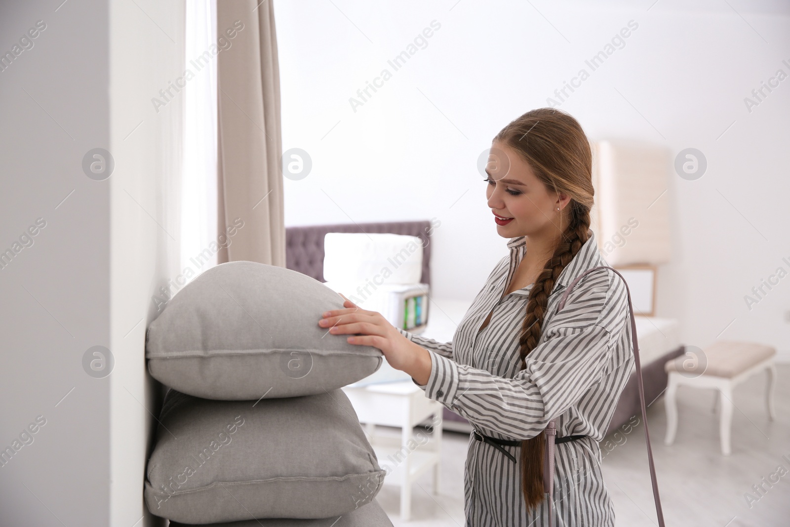 Photo of Young woman choosing cushion in mattress store