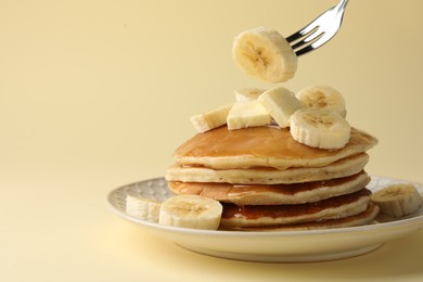 Photo of Eating delicious pancakes with bananas, butter and honey on beige background, closeup. Space for text