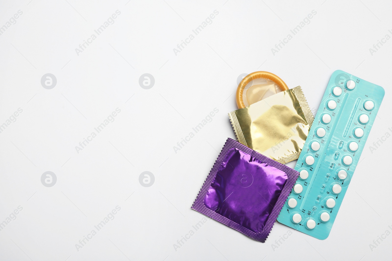 Photo of Condoms and birth control pills on light grey background, flat lay with space for text. Safe sex concept