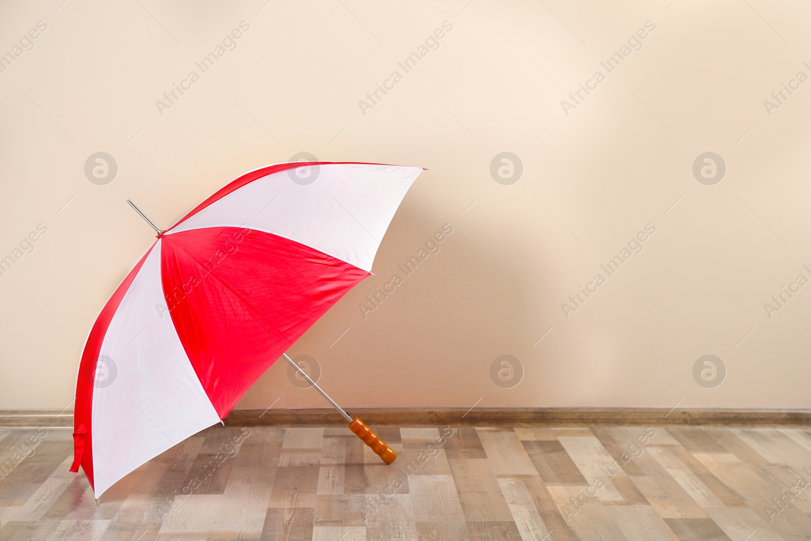 Photo of Beautiful colorful umbrella near beige wall. Space for text