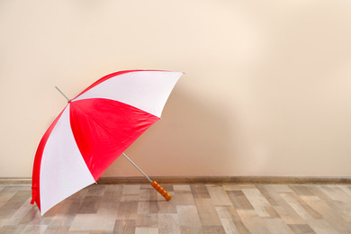 Beautiful colorful umbrella near beige wall. Space for text