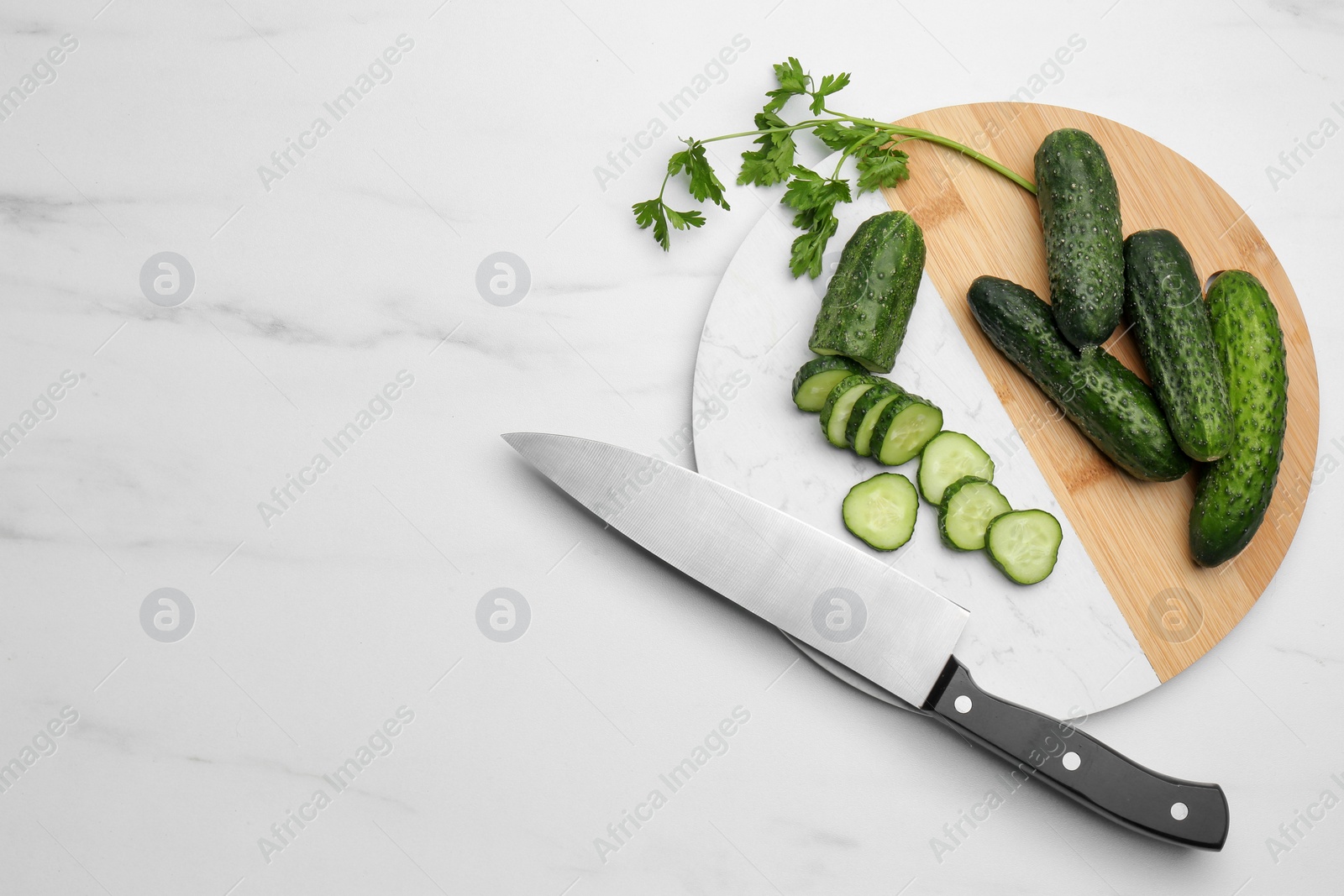 Photo of Fresh ripe cucumbers and parsley on white marble table, flat lay. Space for text