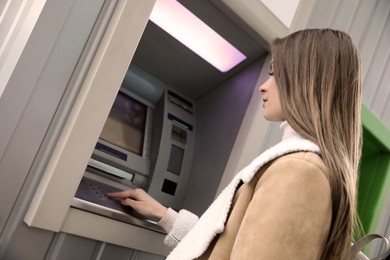 Young woman entering cash machine pin code outdoors