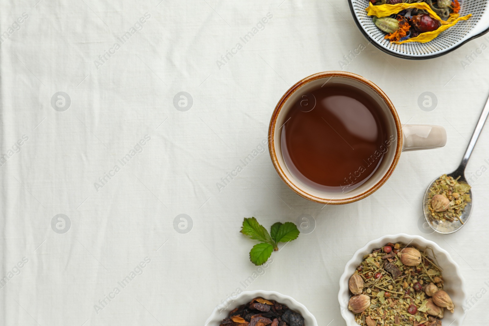 Photo of Cup of freshly brewed tea, dried herbs and berries on white background, flat lay. Space for text