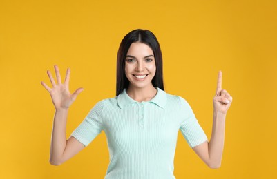 Photo of Woman showing number six with her hands on yellow background