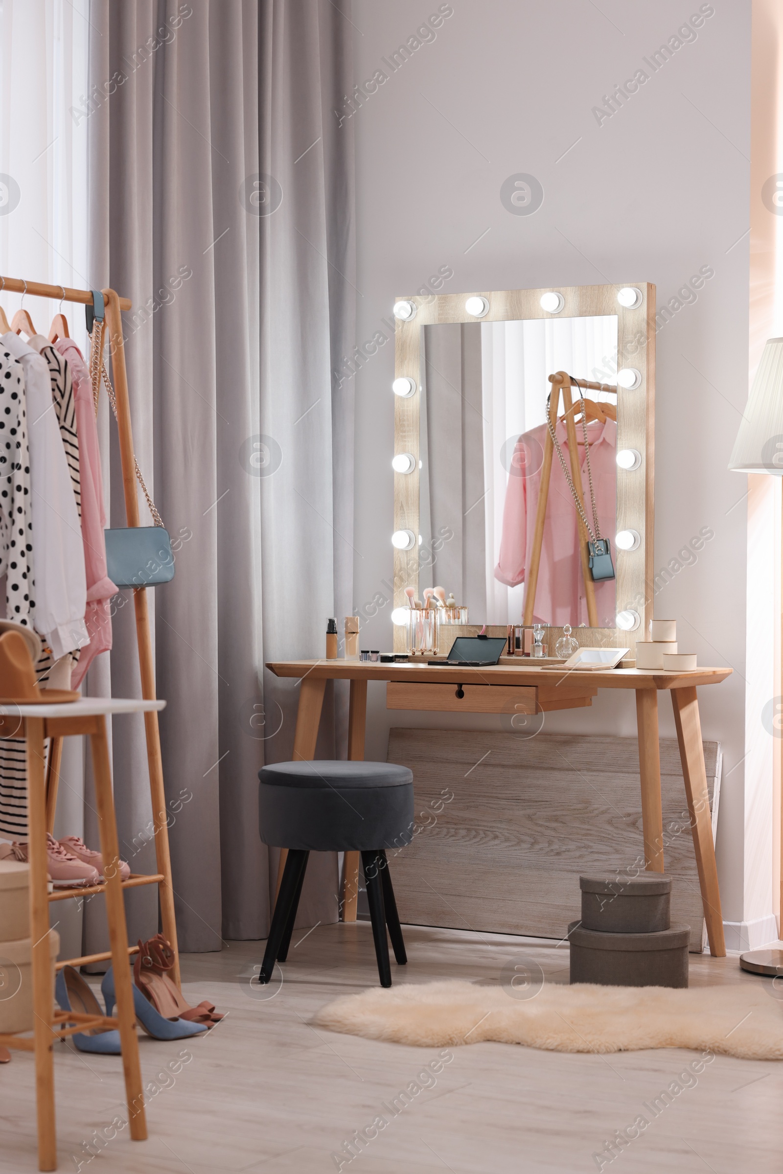 Photo of Makeup room. Stylish mirror with light bulbs on dressing table and chair indoors