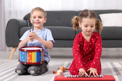 Little children playing toy musical instruments at home