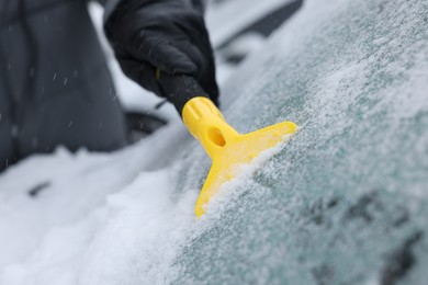 Man cleaning snow from car windshield outdoors, closeup