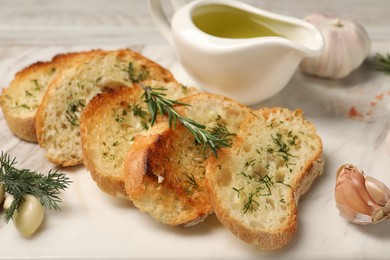 Photo of Tasty baguette with garlic, dill, rosemary and oil on board, closeup