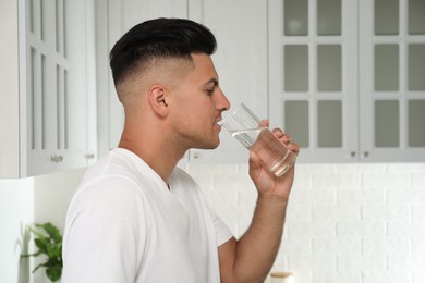 Photo of Man drinking tap water from glass in kitchen